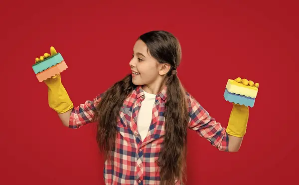 stock image surprised girl housecleaner do chores isolated on red. girl housecleaner do chores in studio. girl housecleaner do chores on background. photo of girl housecleaner do chores with sponge.