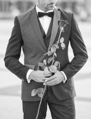 elegant man in tuxedo at romantic occasion. man with romantic present. cropped view of romantic man with rose.