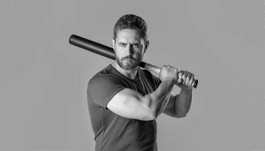 angry man express anger beating with bat isolated on grey background. aggression of angry man with bat in studio. photo of angry man hold bat. angry man threatening.