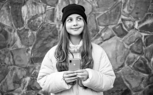 積極的な10代の少女が屋外でブログを 10代の女の子が帽子をかぶって電話でブログを 外の電話でブログしてる10代の女の子の写真 10代の女の子がストーンバックグランドで電話でブログ — ストック写真