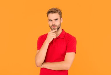 mens beauty. portrait of man with bristle in red shirt. serious young man with beard on yellow background. hair and beard care. confident and handsome unshaven guy. male casual fashion.