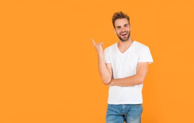 Sarı arka planda sakallı genç bir adam. Saç ve sakal bakımı. Kendine güvenen ve yakışıklı, tıraşsız adam. Erkek modası. Erkek güzelliği. Beyaz gömlekli kıllı adam..