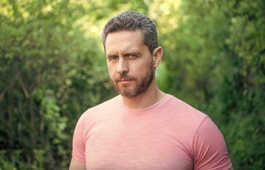 Portrait of handsome unshaven man natural background outdoors.