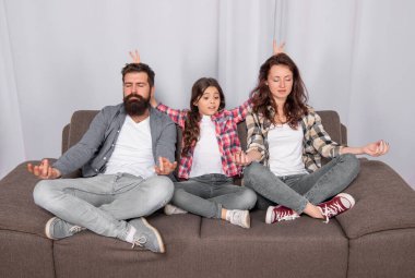 parents with kid maditating together at home, yoga.