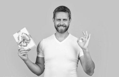 Şu anki kutuyu sarı arkaplanda saklayın, tamam mı? Şu anki kutuyu stüdyoda tutun. Tatil için hediye kutusu olan bir adam. Bir adamın hediye kutusunun fotoğrafı..