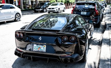 Miami Beach, Florida USA - April 15, 2021: black ferrari F12 berlinetta supercar, side back view.