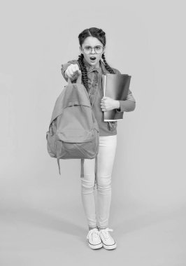 Okul çantasını sarı arka planda tutan öfkeli genç kız. Okul eğitimi. Okula geri dön..