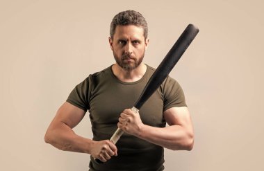 Yarasalı öfkeli holigan adam gri arka planda izole edilmiş. Stüdyoda sopalı holigan adam. Sopalı holigan adamın fotoğrafı. Yarasayla tehdit eden holigan adam..