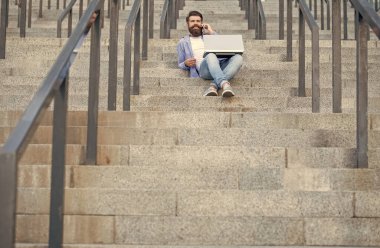 Adamın dizüstü bilgisayarında video bağlantısı var, kopyalama alanı. Adamın dışarıda online video iletişimi var. Adamın dışarıda çevrimiçi video bağlantısı var. Adamın merdivenlerde online video bağlantısı var..