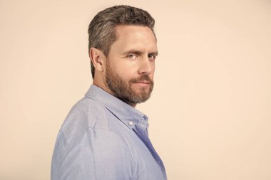 Gri arka planda sakallı ve fotokopi alanı olan olgun bir adamın yüzü. Stüdyoda sakallı, olgun bir adam. Sakallı, olgun bir adamın fotoğrafı. Kirli sakallı, normal gömlekli olgun bir adam..