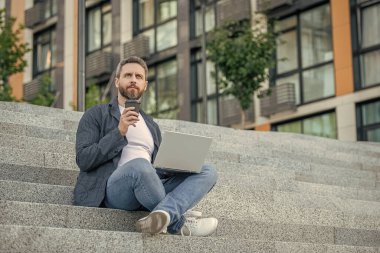 Bilgisayarlı serbest çalışan bir adamın resmi. Dışarıda dizüstü bilgisayarı olan serbest çalışan bir adam. Sokaktaki serbest çalışan adam. Dışarıda polisle serbest çalışan bir adam..