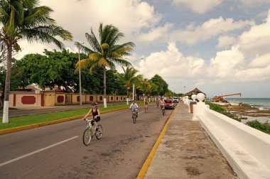 Cozumel, Meksika - 24 Aralık 2015: Bisikletli insanlarla deniz kenarında yaz caddesi.