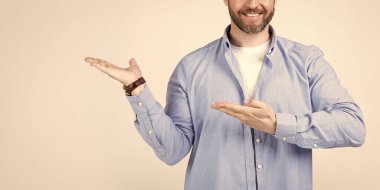 Reklam sunan kırpılmış adam Grey 'de izole edilmiş, kopyalama alanı. Stüdyoda reklamları sunan adam. Bir adamın sunduğu ve sunduğu bir fotoğraf. Adam sunar ve sunar