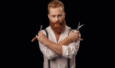 Siyahlar içindeki yakışıklı berber dükkanı sahibi. Stüdyodaki berber. Makas ve jiletle berber dükkanı işleten adam. Arka planda berber dükkanındaki adamın fotoğrafı.