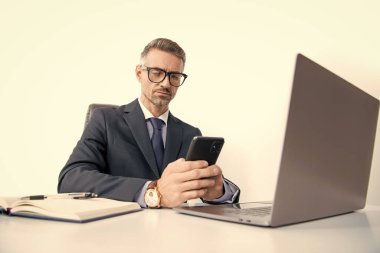 Ofiste bilgisayarlı telefon kullanan gözlüklü meşgul bir adam..