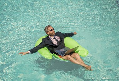 Rahat adam ticareti ve rahatlama. Adam tüccar işi ve yüzme havuzunda rahatlamak. Adam tüccar işi ve dizüstü bilgisayarla rahatla. İnsan ticaretinin fotoğrafı ve havuzda rahatlamak..