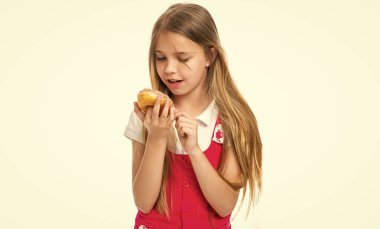 Arka planda lezzetli donutu olan meraklı genç kız. Lezzetli donutlu genç bir kızın fotoğrafı. Lezzetli çörekleri olan genç bir kız. Stüdyoda lezzetli donutu olan genç kız..