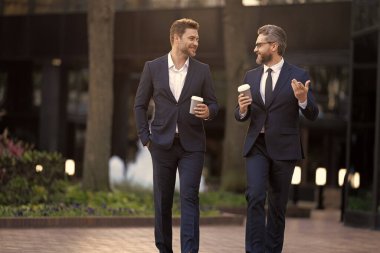 Yöneticinin kahve içerken çekilmiş iş görüşmesi fotoğrafı. Yönetici sokakta iş konuşuyor. Yönetici dışarıda iş konuşuyor. Takım elbiseli yönetici kahve tutarak iş konuşuyor..