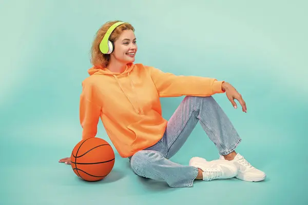 sporty woman loves music sitting isolated on blue. sporty woman listen music in studio. sporty woman listening music on background. photo of sporty woman loves music.