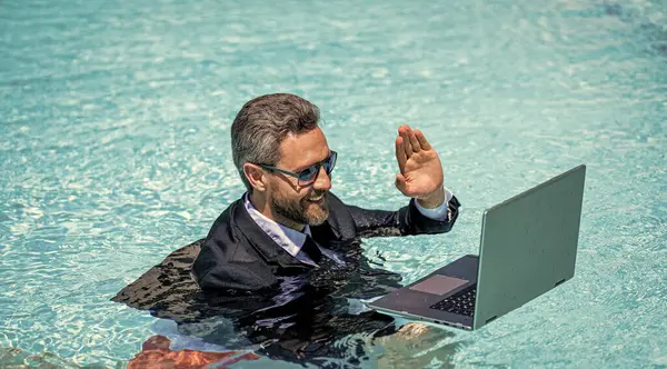 man has business video call in weekend refreshing at pool, hello. man has business video call in weekend with laptop. photo of man has business video call in weekend. man has business video call
