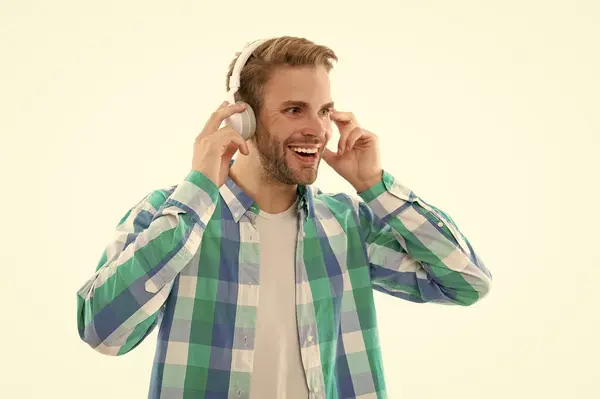positive millennial man listening music on background. photo of millennial man music lover. millennial man listen music isolated on white. millennial man wear music headphones in studio.