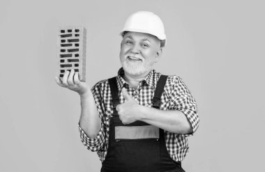 Sarı arka planda miğferli yaşlı adam. başparmak yukarı.