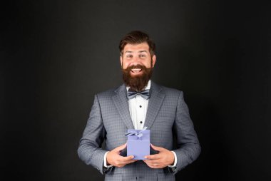 Smokinli, papyon takan, siyah arka planda, ödül kutulu mutlu bir adam. özel selamlama.