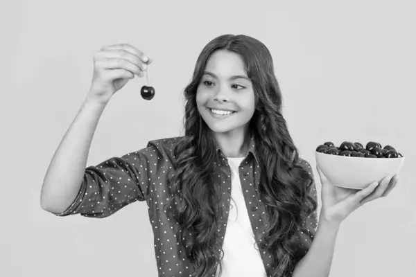 stock image happy teen girl hold cherry bowl on yellow background.