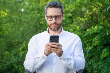 İş analisti açık havada telefonla çalışıyor. İnternette çalışan iş analisti. İnternette çalışan iş analistinin fotoğrafı. İş analisti online çalışıyor.