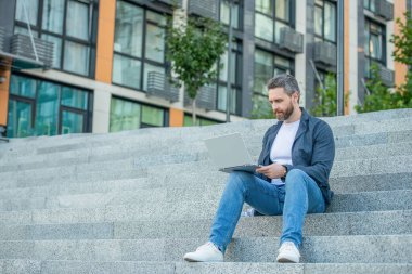 Bilgisayarlı serbest çalışan bir adamın reklam fotoğrafı. Dışarıda dizüstü bilgisayarı olan serbest çalışan bir adam. Sokaktaki serbest çalışan adam. Dışarıda polisle serbest çalışan bir adam..