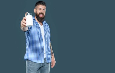Gülümseyen olgun bir adam gri arka planda ilaç kavanozunu tutar..