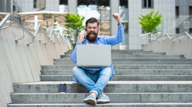 Kazanan adamın cep telefonuyla konuşması heyecan verici. Kazanan merdivenlerde oturarak bahsi kazanır. İnternette bahis oynuyorum. Mobil bahis. Kazanmak için bahis.