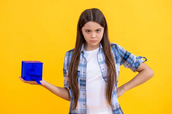teen girl holding a present wrapped. serious teen girl show present on occasion. teen girl with present. teen girl holding present box with excitement at birthday party. bad mood about a gift.