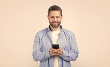 Stüdyoda mesajı olan mutlu bir adam. Erkek telefonundan mesaj var. Mesaj atan adamın fotoğrafı var. Stüdyo arka planına izole edilmiş bir şekilde telefonla mesaj yaz..