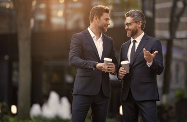 Yönetici dışarıda iş konuşuyor. Takım elbiseli bir yönetici kahve içerken iş konuşuyor. Yöneticinin kahve ile iş görüşmesi imajı. Yönetici sokakta iş konuşuyor..