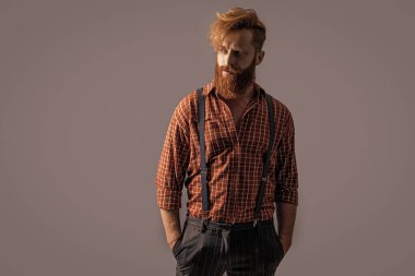 Arka planda jartiyer giymiş, erkek giyim retro hipster adam. Pantolon askısı takmış hipster bir adamın fotoğrafı. Askılı eski hipster adam gride izole edilmiş. Stüdyoda askılı hipster adam..