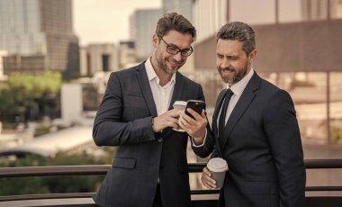 Gülümseyen işletme yöneticisinin fotoğrafı. Çek telefonu. İşletme yöneticisi caddedeki kontrol telefonu. İşletme yöneticisi dışarıdaki telefonu kontrol et. Takım elbiseli bir işletme yöneticisi. Elinde kahve tutan bir çek..