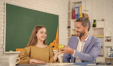 Sınıfta hocasıyla elma paylaşan neşeli bir çocuk..