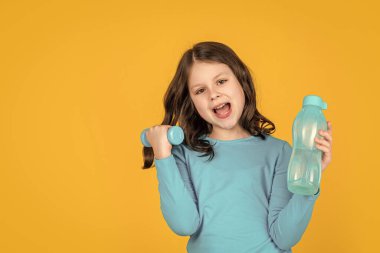 Sarı arka planda halter ve spor şişesi olan mutlu çocuk..