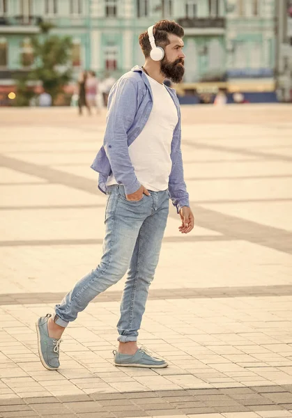 handsome hipster in music earphones outside. hipster in music earphones in the street. photo of hipster in music earphones. hipster in music earphones outdoor.