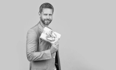 positive guy hold present box in studio. guy with present box for holiday. photo of guy holding occasion present box. guy hold present box isolated on yellow background.