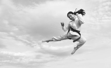 martial art concept. teen girl practicing martial art. girl martial fighter jump on sky background.