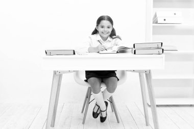 photo of teen school girl noting and smile. teen school girl noting in classroom. teen school girl noting at the table. teen school girl noting in notebook.
