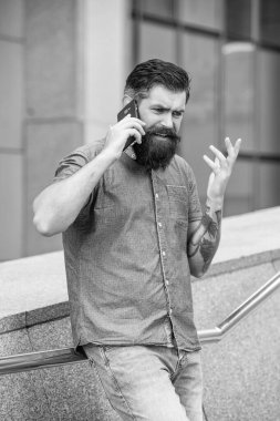 photo of worried man speak on smartphone. man speak on smartphone outdoor. man speak on smartphone outside. man speak on smartphone in the street.