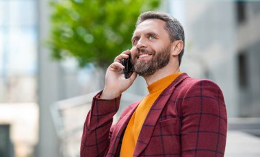 Neşeli bir adamın sokakta cep telefonu araması. Dışarıdaki cep telefonundan arayan bir adam. Adamın cep telefonundan aradığı ve konuştuğu fotoğraf. Adamın dışarıda cep telefonu görüşmesi var..