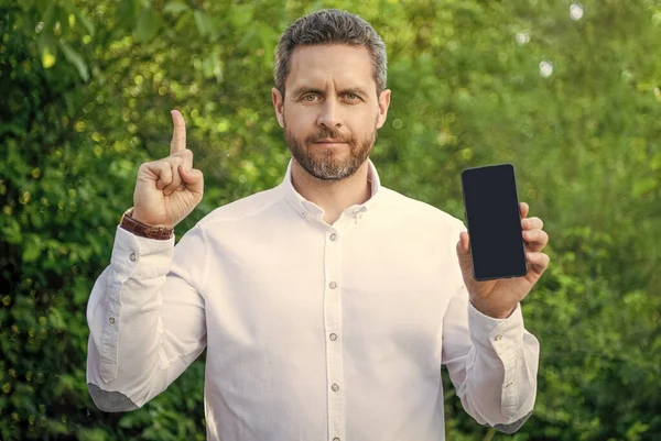 inspired businessman showing app on phone. photo of businessman showing app with copy space. businessman showing app. businessman showing app outdoor.