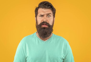 Sarı stüdyo arka planında izole edilmiş şaşkın sakallı adamın portresi..
