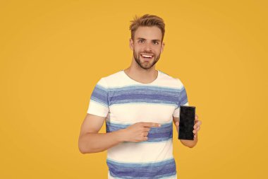 Genç milenyum adamı telefon uygulaması gösteriyor. Milenyum adamı telefonu gösteriyor. Milenyum adamı stüdyoda telefon ekranını gösteriyor. Genç milenyum adamı telefon kopyalama alanı gösteriyor.