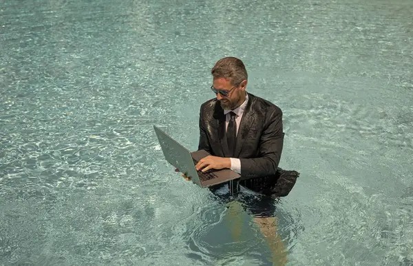 businessman has freelance business in swimming pool, copy space. businessman has freelance business with laptop. photo of businessman has freelance business in pool. businessman has business online.