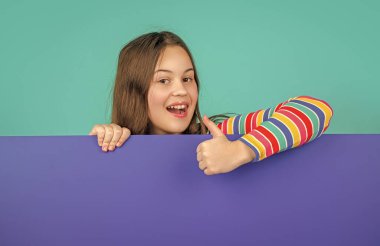 Boş mavi kağıdın arkasında reklam için fotokopi alanı olan mutlu bir çocuk. başparmak yukarı.